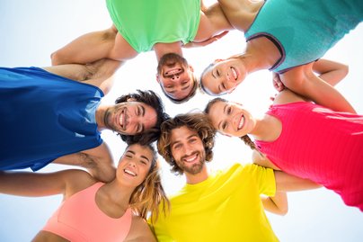 Menschen in bunten T-Shirts stehen im Kreis 