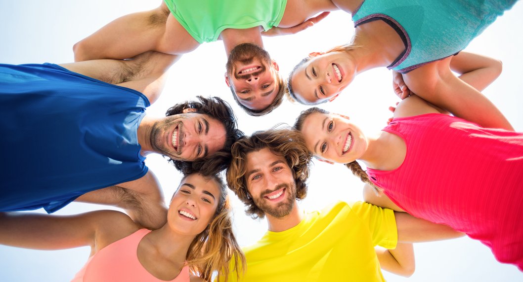 Menschen in bunten T-Shirts stehen im Kreis 