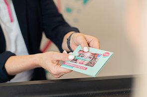 Frau die Gutscheinkarte überreicht - man sieht nur die Hände und die Gutscheinkarte