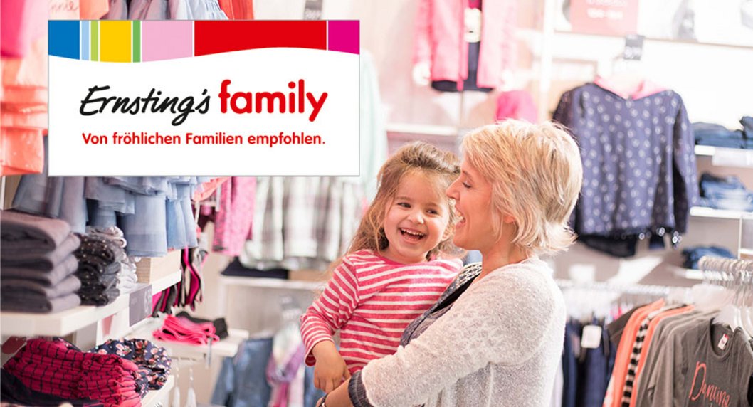 Ernstings Family Logo auf Foto mir lachender Mutter und Mädchen am Arm in einem Kleidungsgeschäft