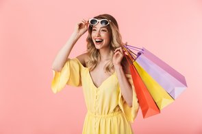 Lachende Frau mit Sonnenbrille und Einkaufstaschen 