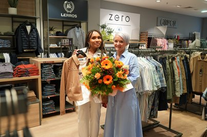 Sabine Riederer mit Blumenstrauß in der Hand und Mitarbeiterin von ZERO-Lerros bei Wiedereröffnung