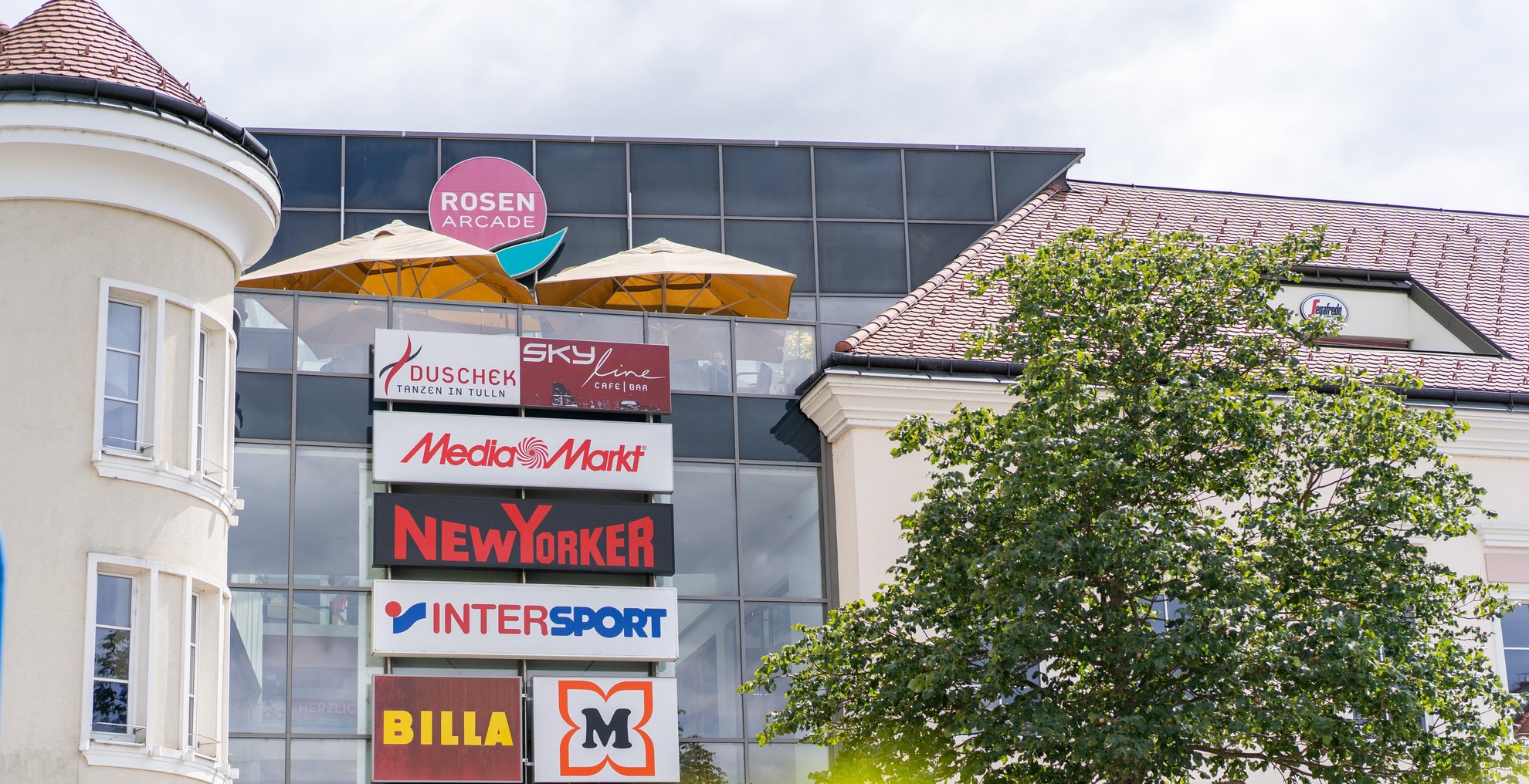 Foto von der Rosenarcade im Frühling mit den Shop Logos sichtbar