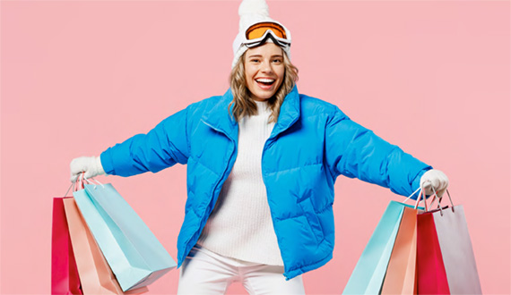 Frau mit blauer Jacke und Haube mit Einkaufstaschen in der Hand
