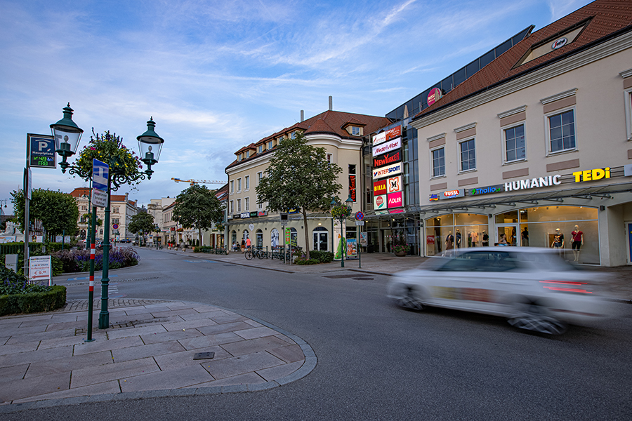 Rosenarcade von außen mit vorbeifahrendem Auto
